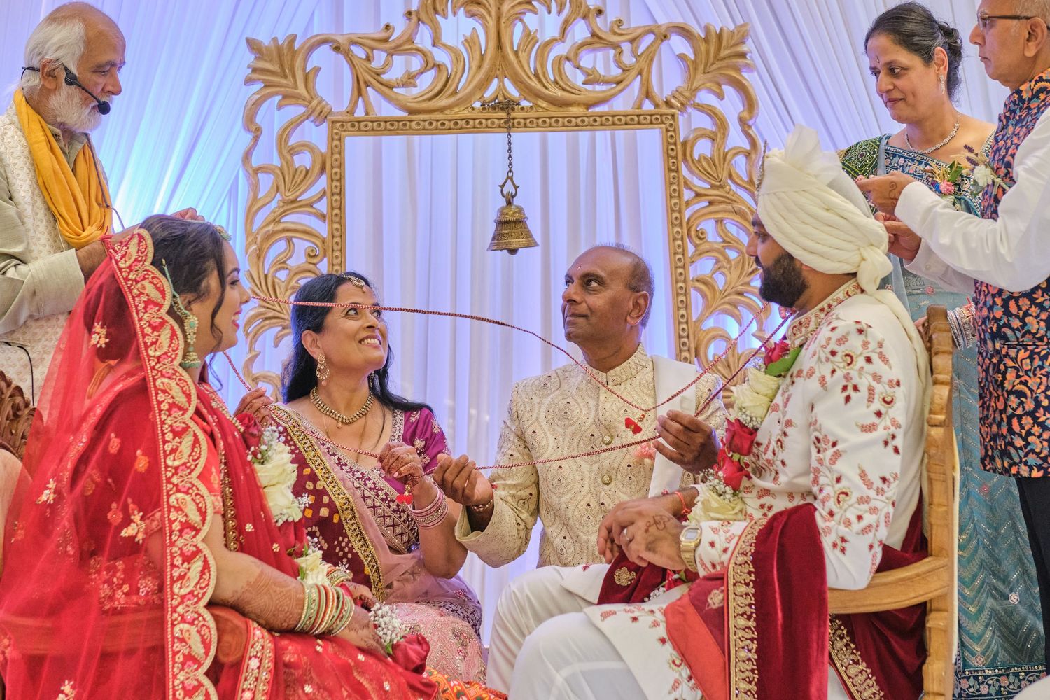 Festive Indian wedding ceremony with guests in traditional attire gathered under elegant white and blue decor.