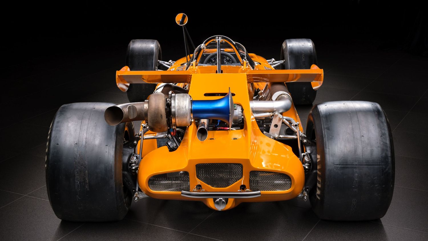 Six connected photos show different angles of an orange McLaren Formula 1 race car against a dark background.