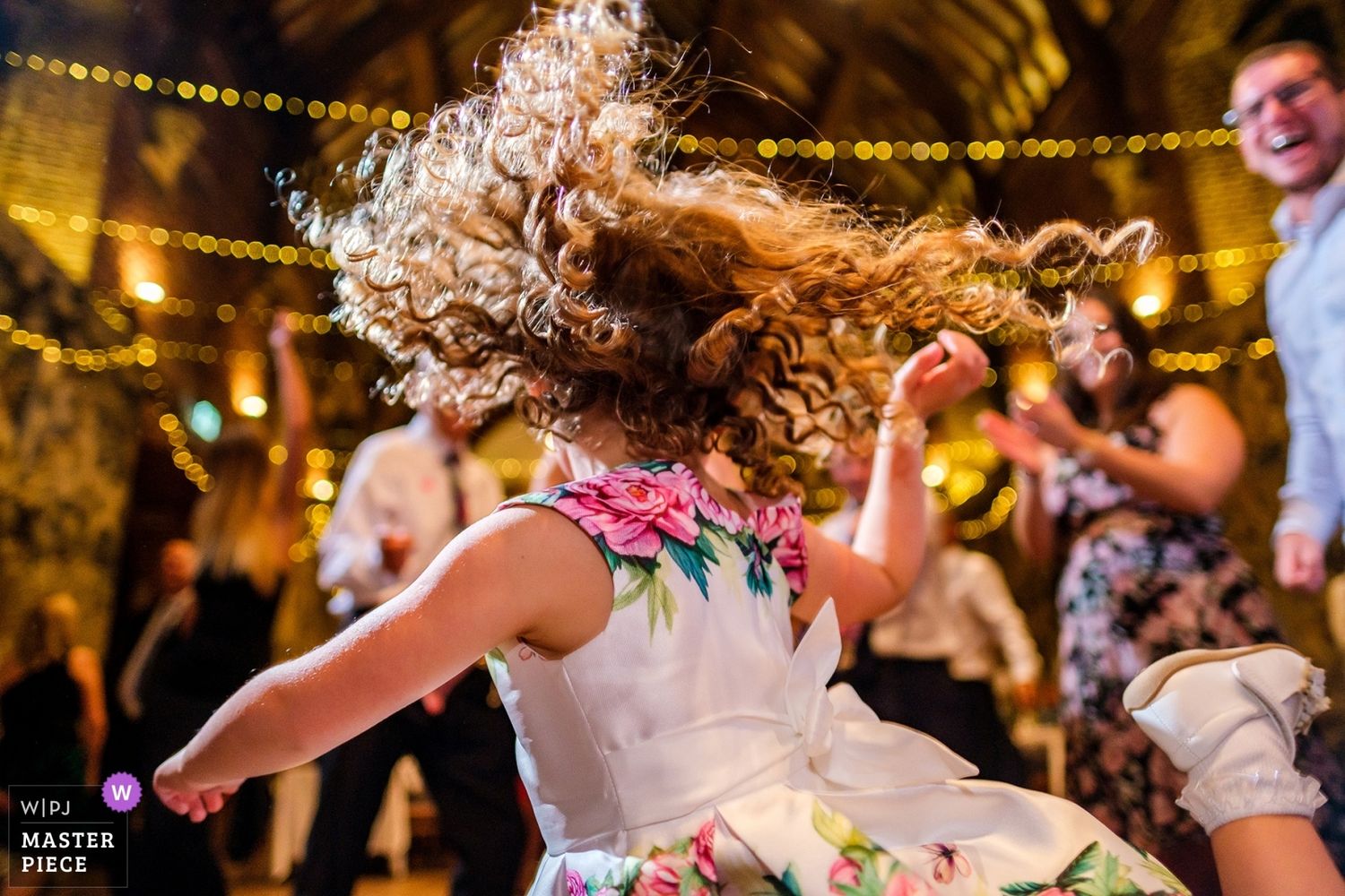 Wedding reception dance floor filled with guests celebrating under string lights.