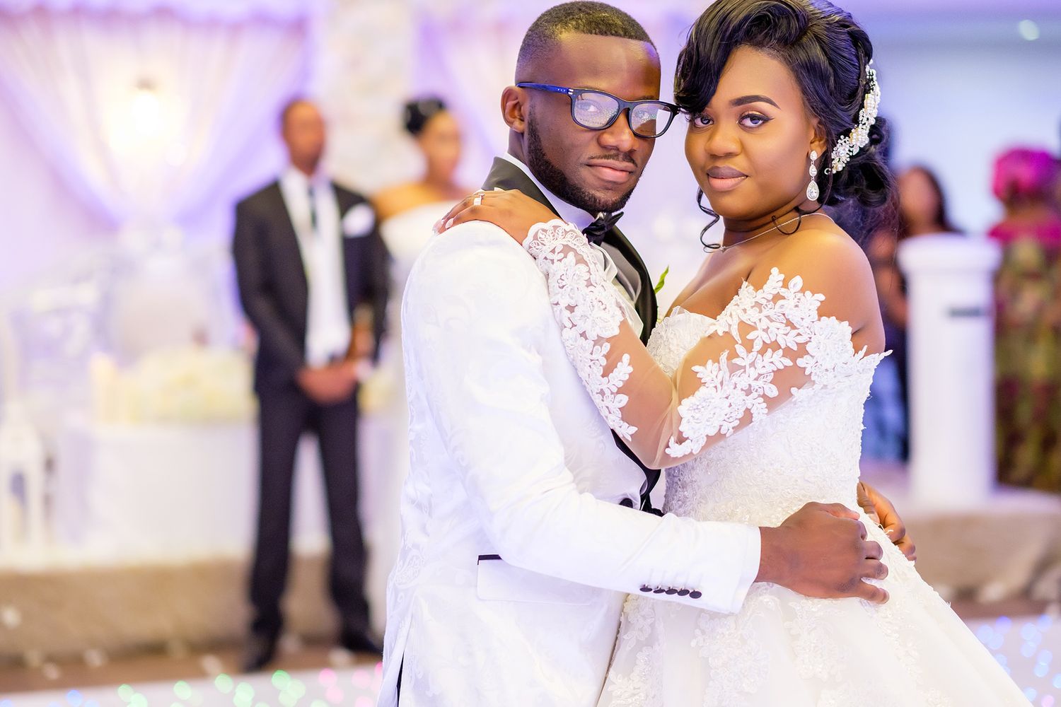 Wedding celebration with purple lighting and elegant decor at an indoor venue.