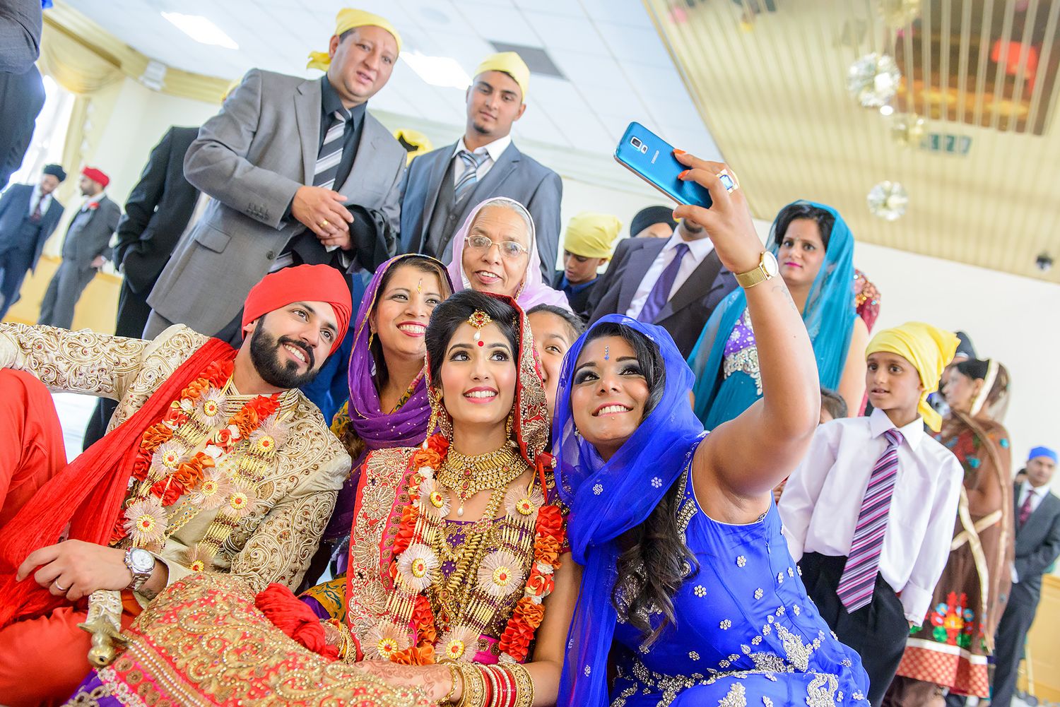 Wedding celebration with guests in vibrant blue and red traditional attire.