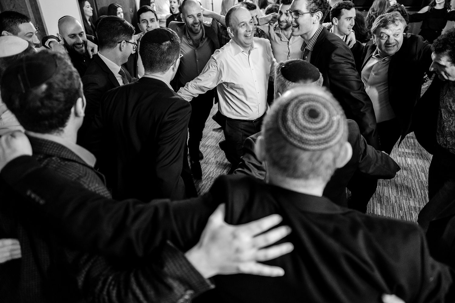 Candid black and white shot of party guests dancing and celebrating in a crowded space.
