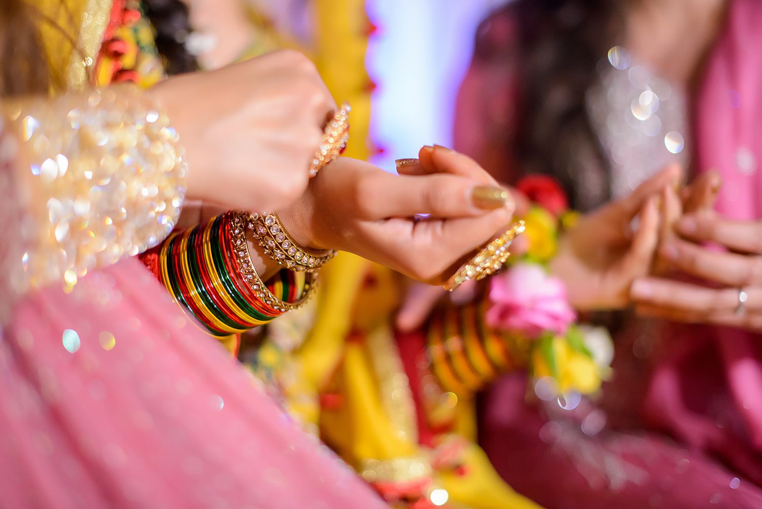 Close-up of hands performing traditional Indian wedding rituals with colorful decorative elements.