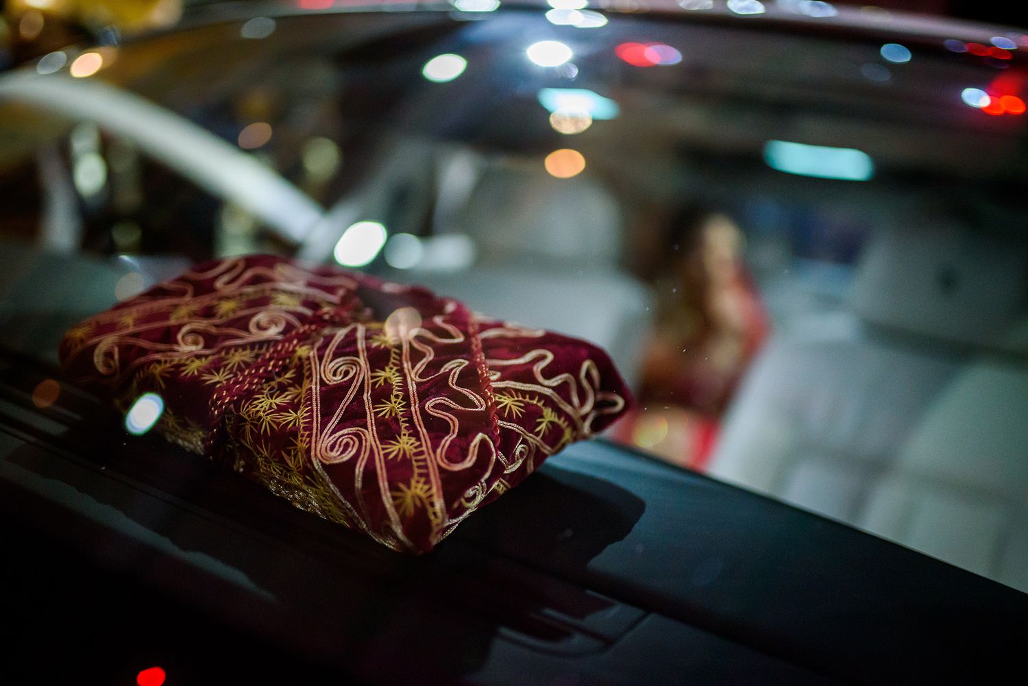 Close-up of ornate red and gold embroidered fabric detail in low light.