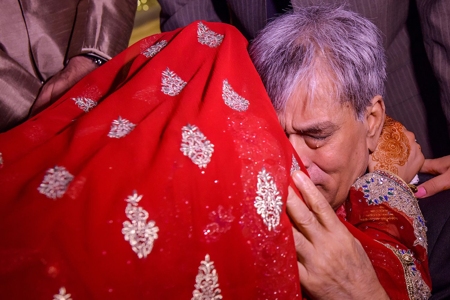 Red traditional wedding attire with intricate silver embroidery patterns.