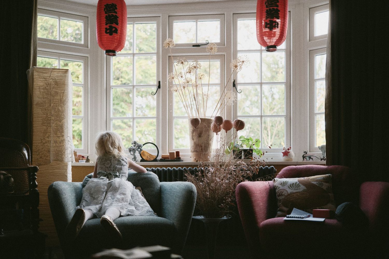 Cozy restaurant interior with red lanterns and large windows letting in natural light.