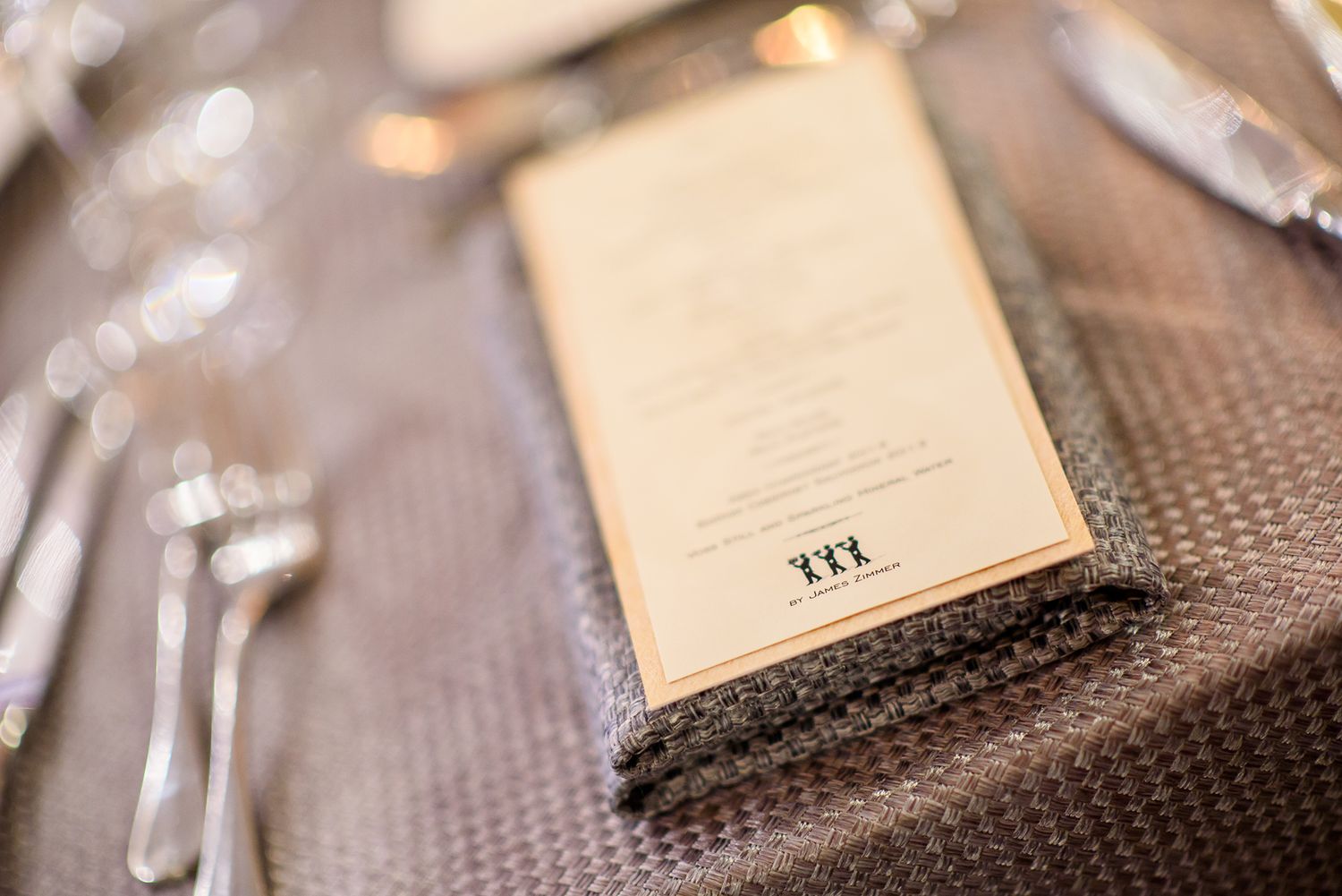 Close-up of formal place settings with menu cards and elegant tableware at an upscale event.