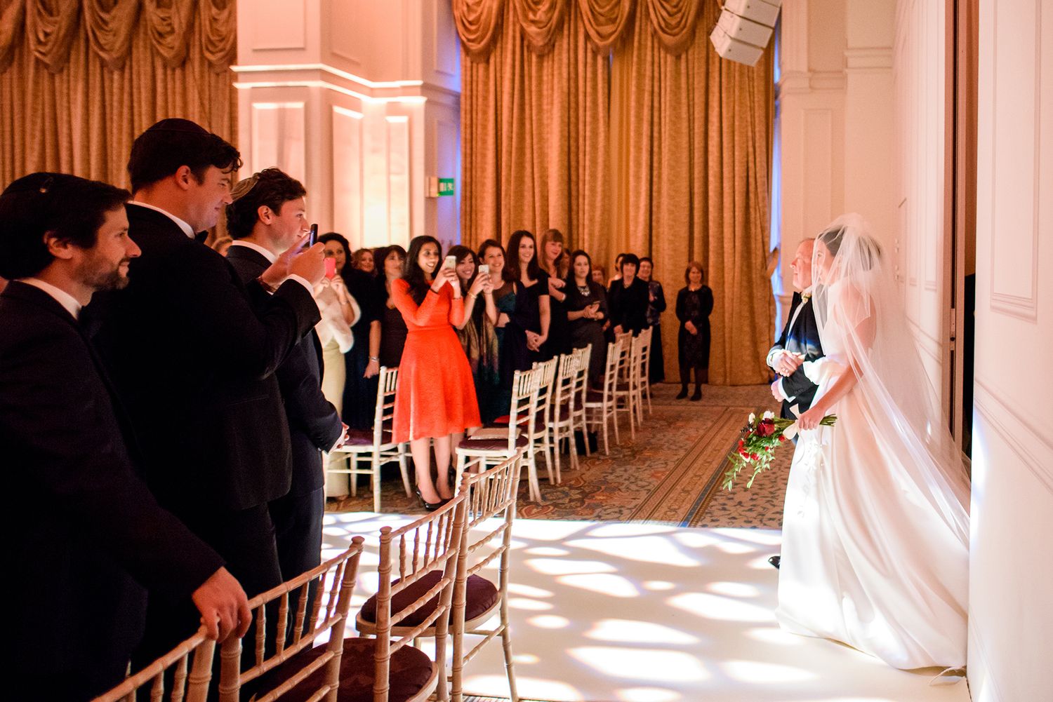 Elegant wedding ceremony setup with white chairs and floral arrangements in a classic ballroom.