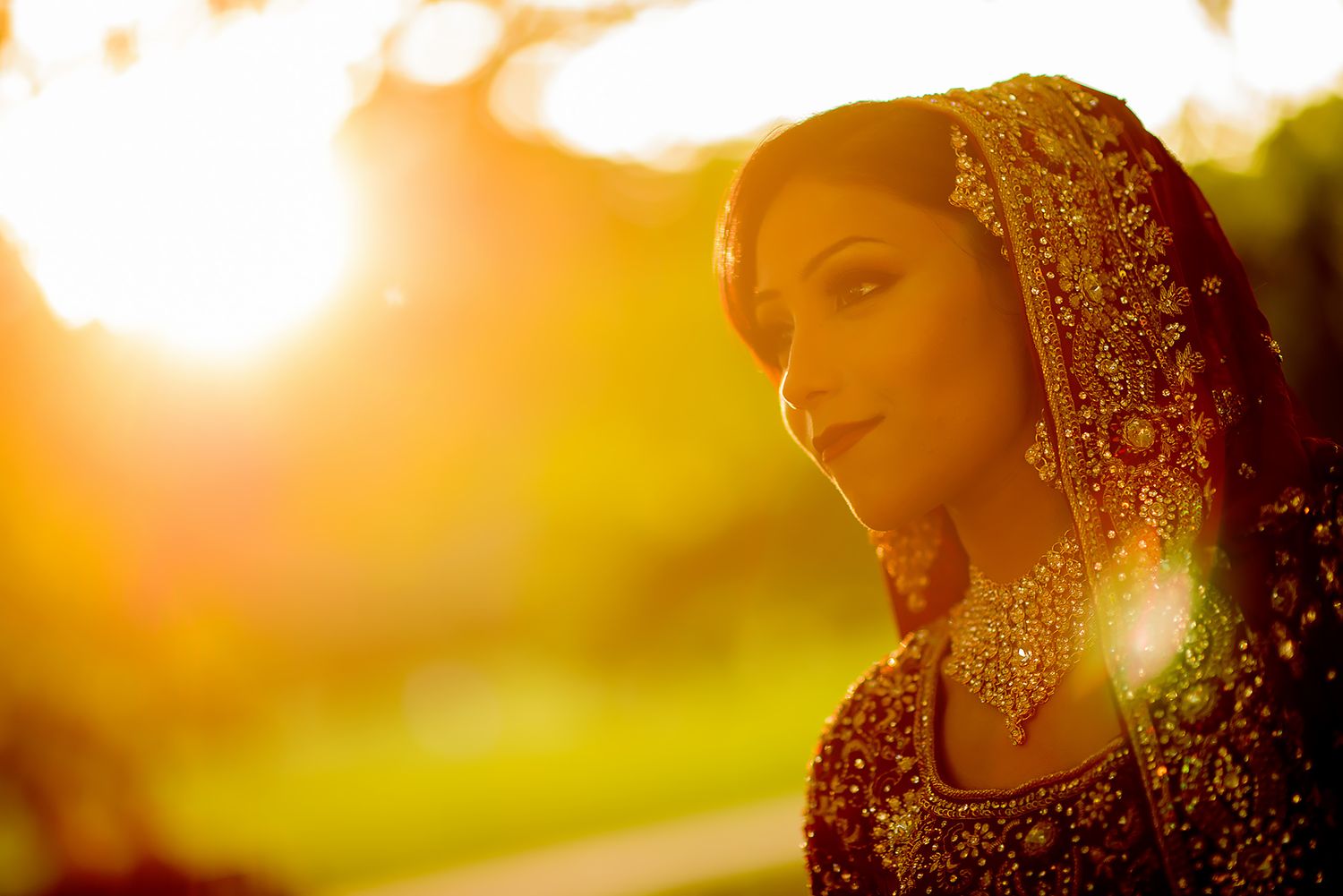 Traditional Indian bridal attire with intricate red and gold embroidery shown in warm sunset lighting.