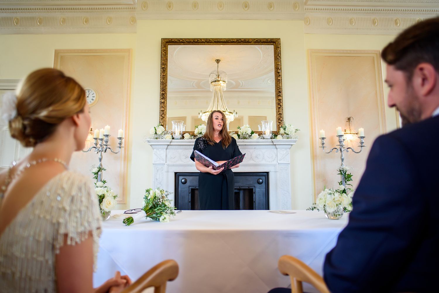Elegant wedding reception setup with chandelier lighting and formal table settings.