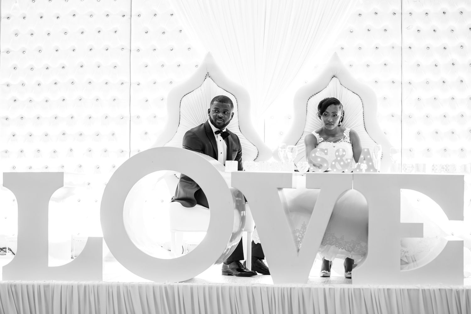 Minimalist white wedding decor with large LOVE letters as backdrop.