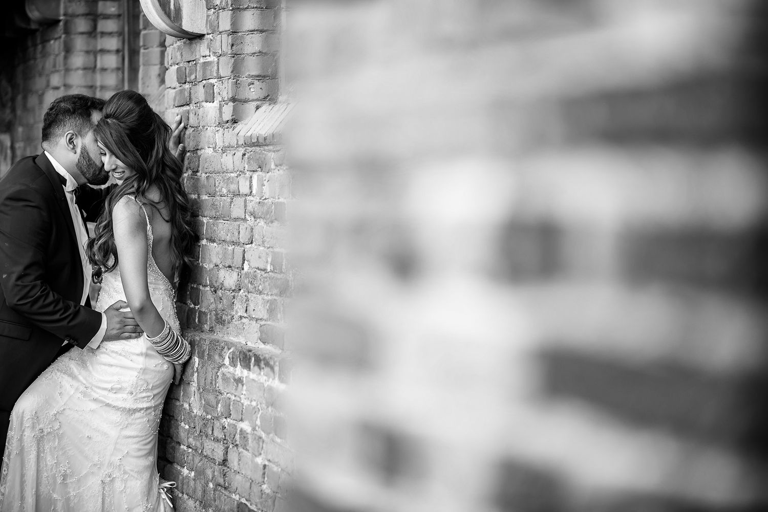 A romantic wedding photoshoot featuring dramatic black and white portraits against textured brick walls.