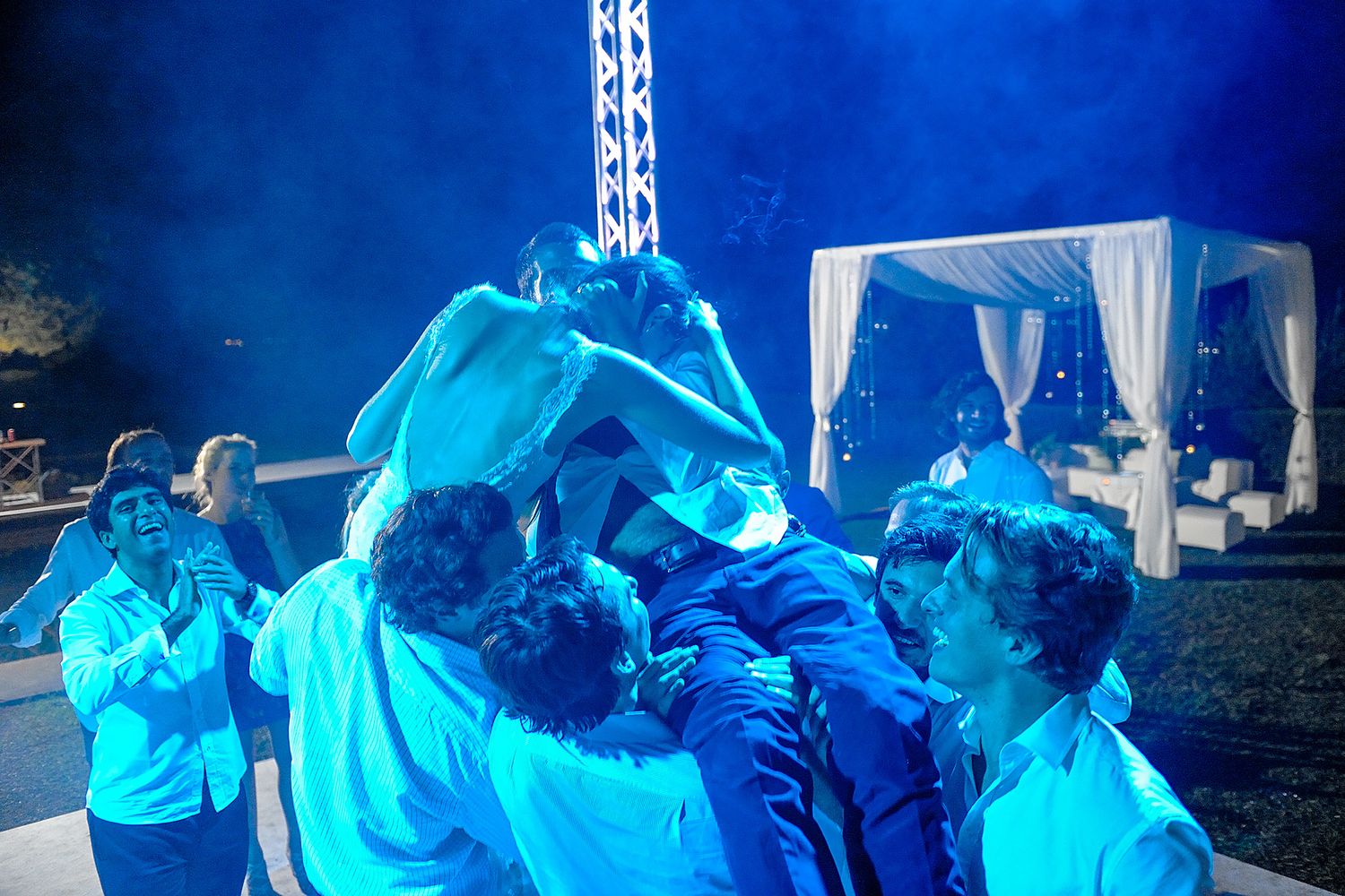 Group celebration captured in cool blue tones during nighttime outdoor event.