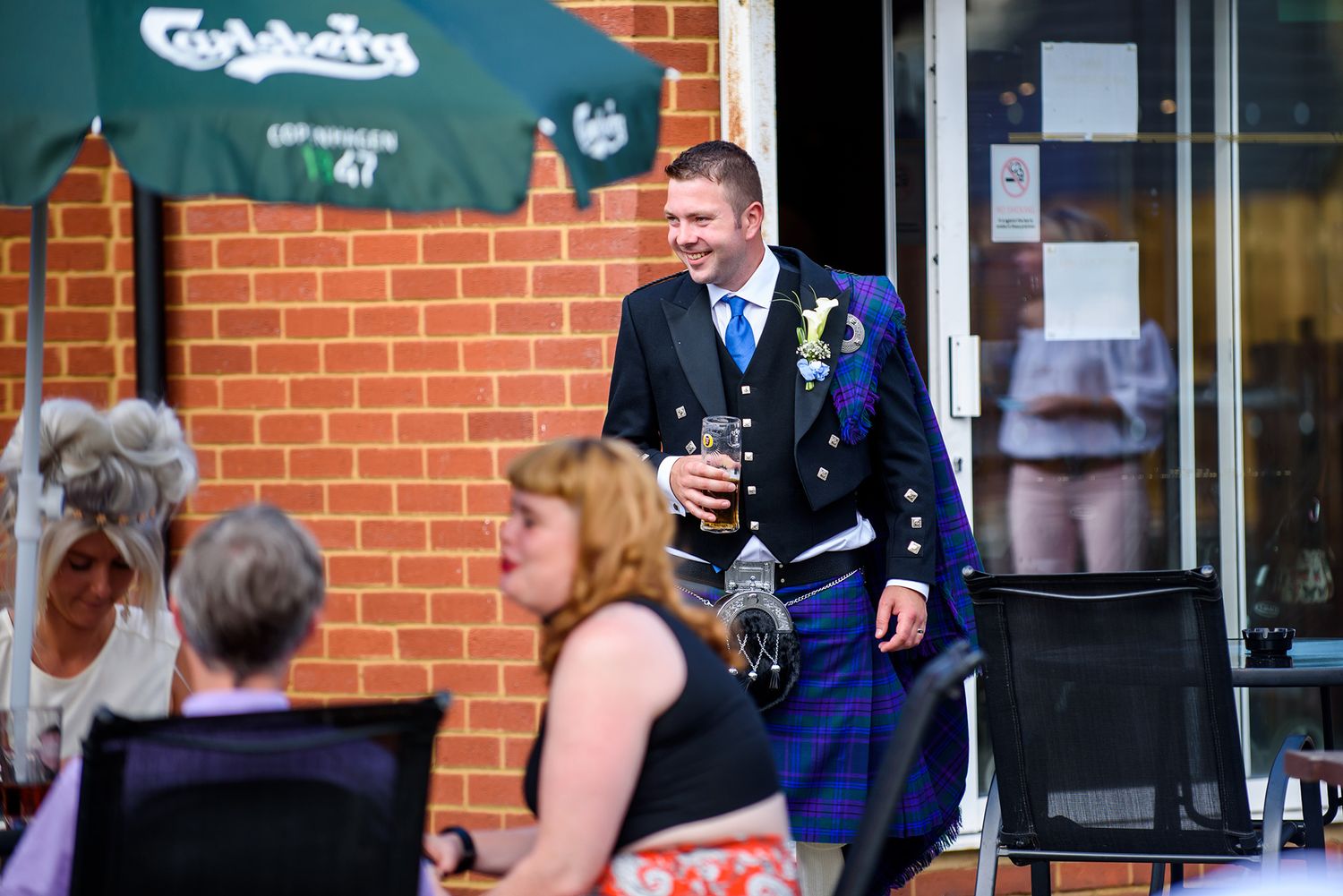 Wedding party gathered outside brick building during celebration.