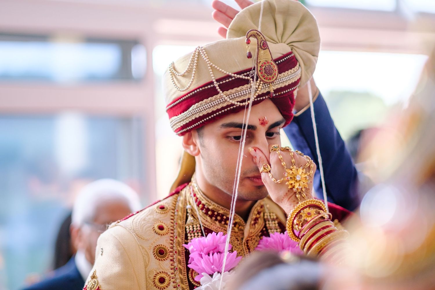 Close-up view of an ornate Indian bridal headpiece with pink and gold beaded details during a ceremony.