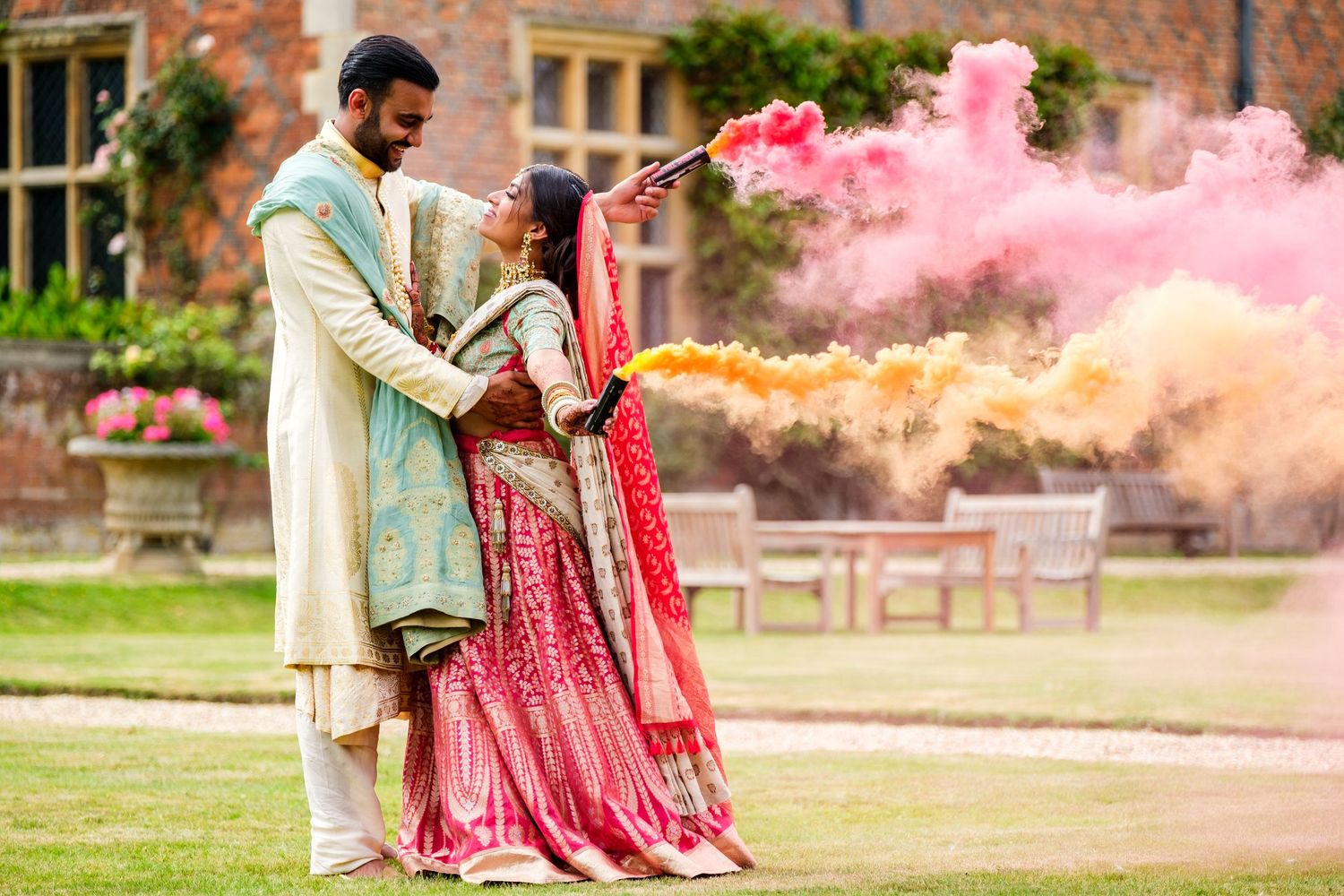 Colorful outdoor celebration with pink smoke effects and traditional Indian attire.