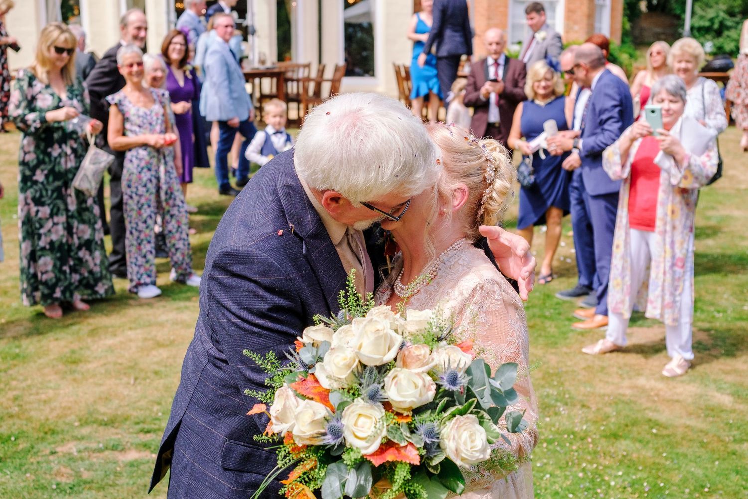 Guests mingle on a lawn during an elegant outdoor wedding reception with floral arrangements.