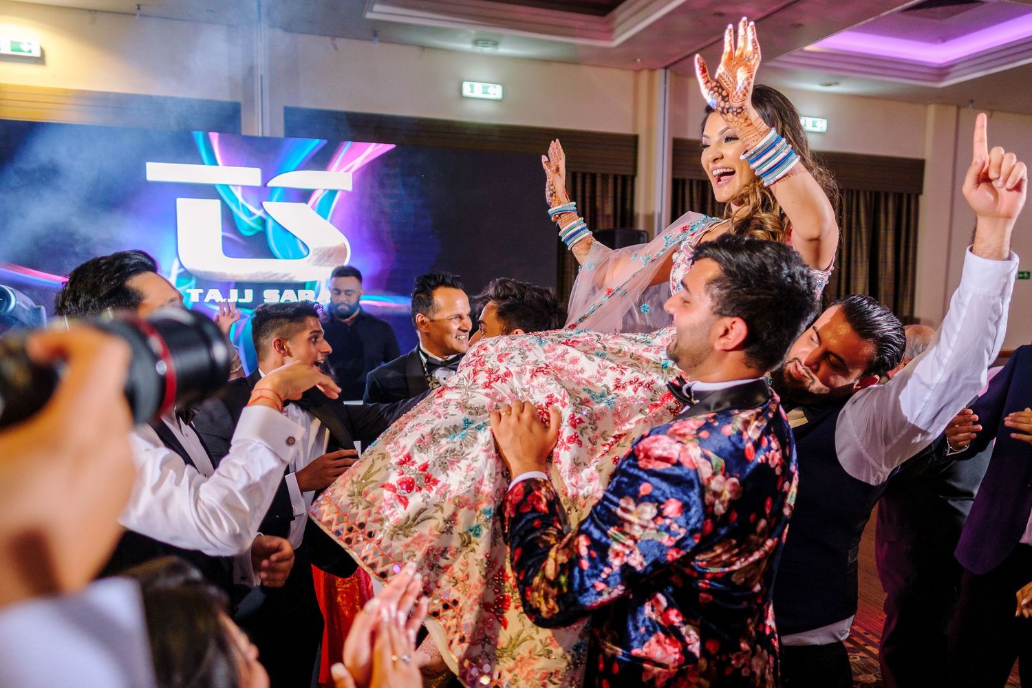 Wedding reception dance party with colorful lighting and guests dancing.