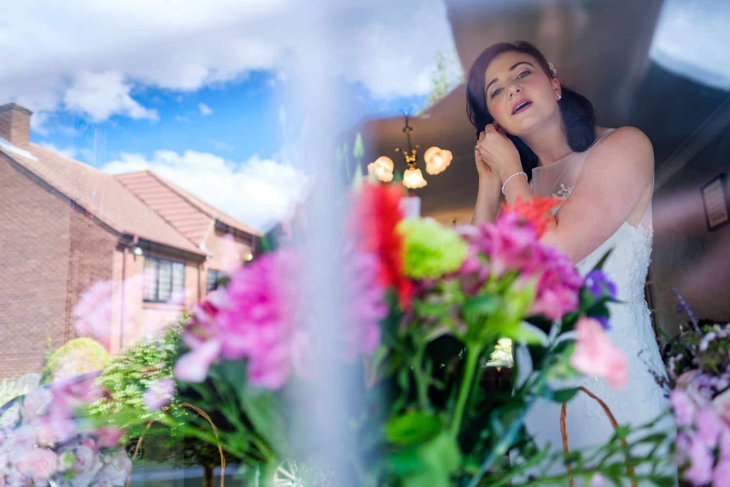 Outdoor wedding photography scene with pink flowers in the foreground creating a romantic garden atmosphere.