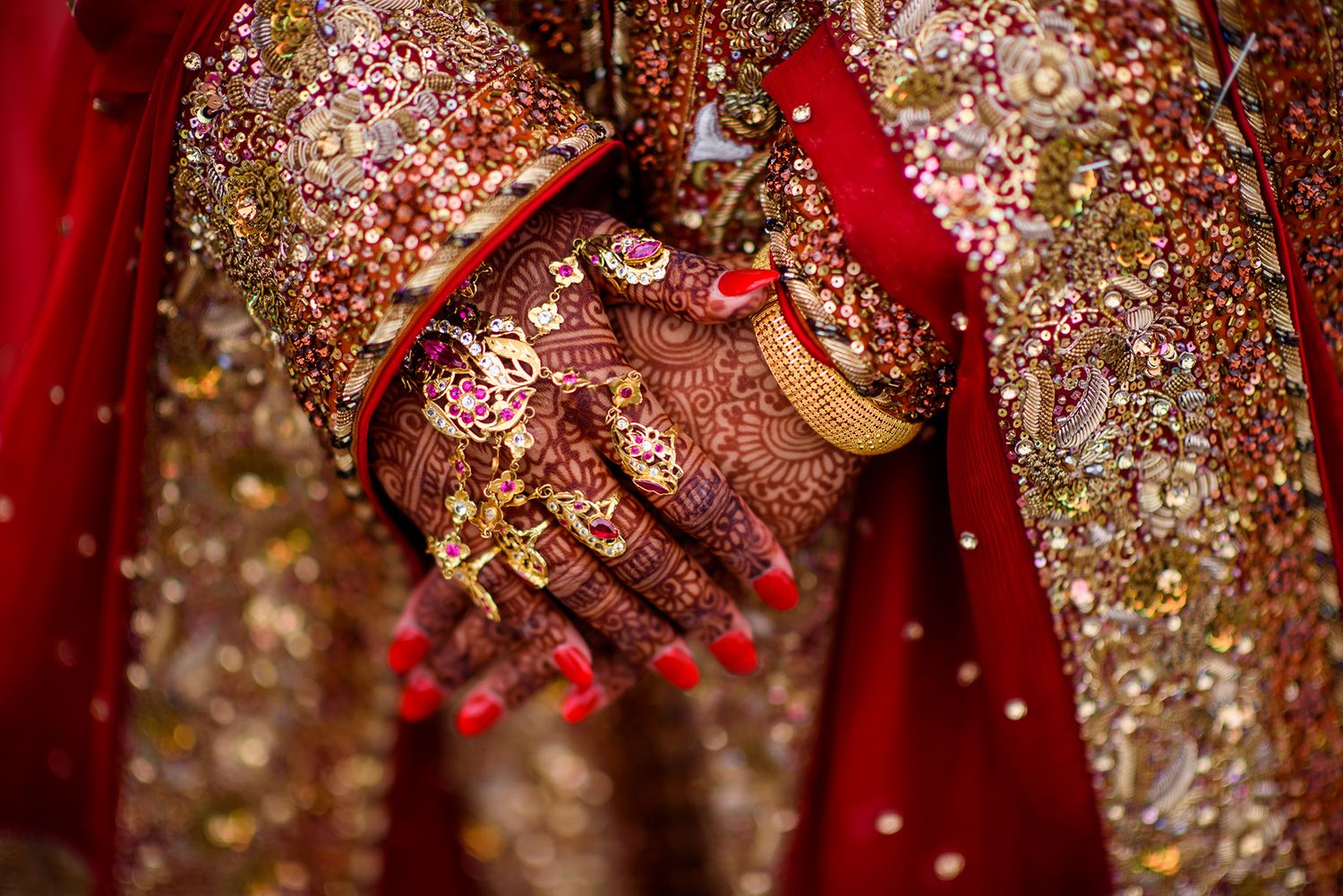 Detailed shots of ornate gold embroidery and beadwork on deep red traditional South Asian wedding attire.