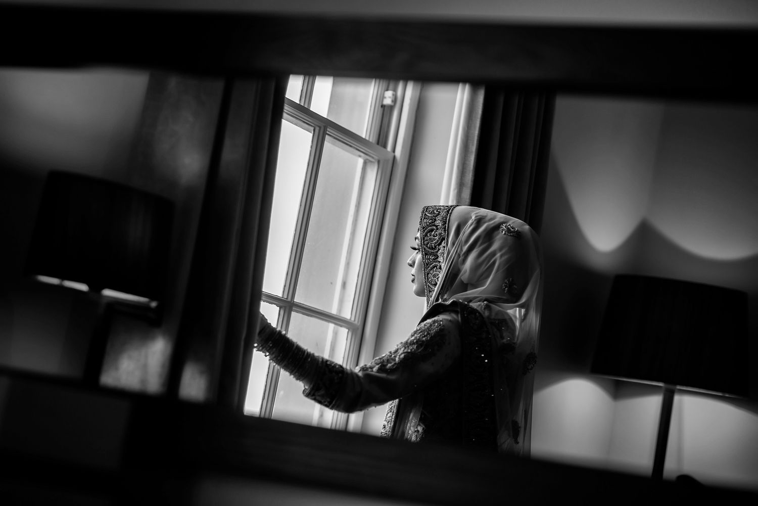 A silhouette through a window frame creates a moody atmospheric scene.