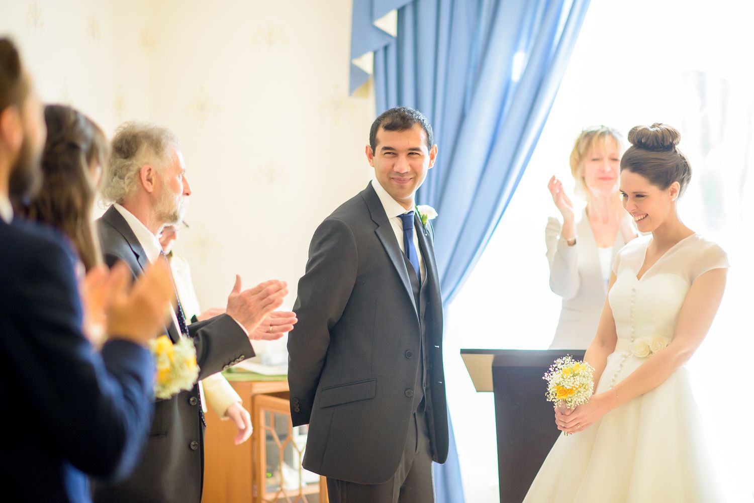 Wedding party celebrating in an elegant indoor venue with natural lighting.