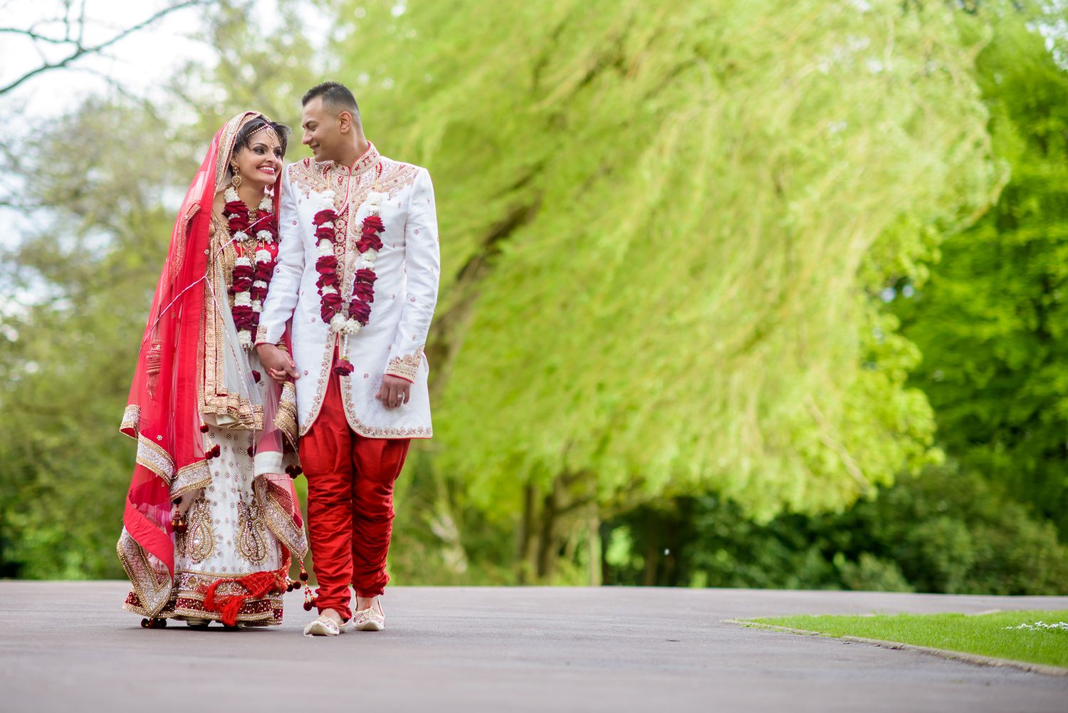 Garden wedding photography session with traditional red and white Indian wedding attire.