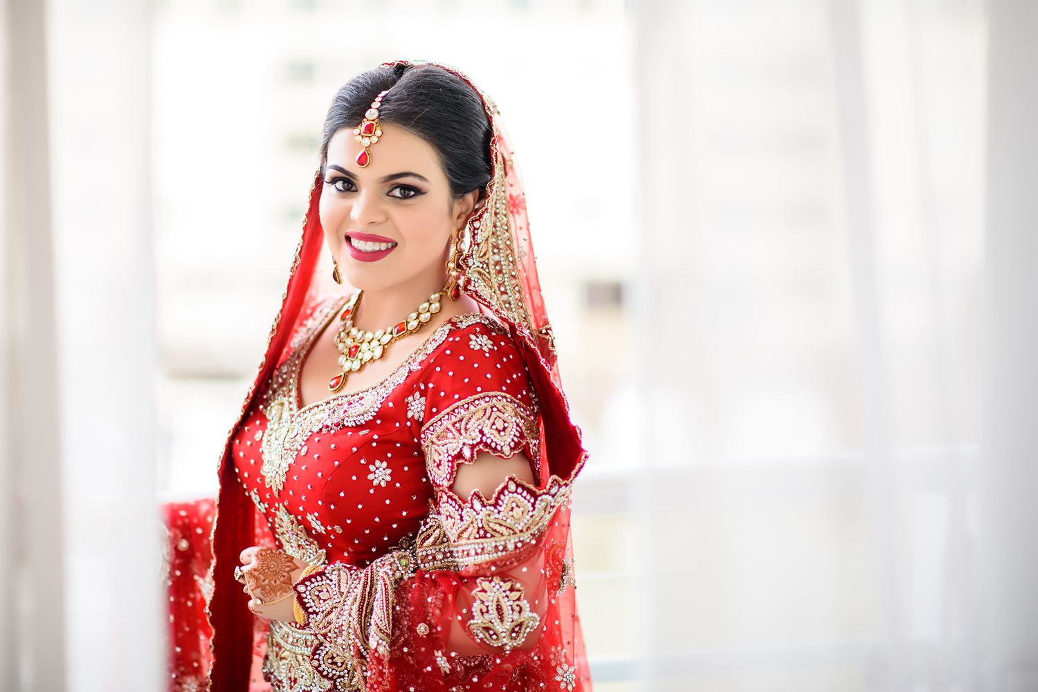 Traditional red and gold South Asian bridal outfit photographed in natural light.