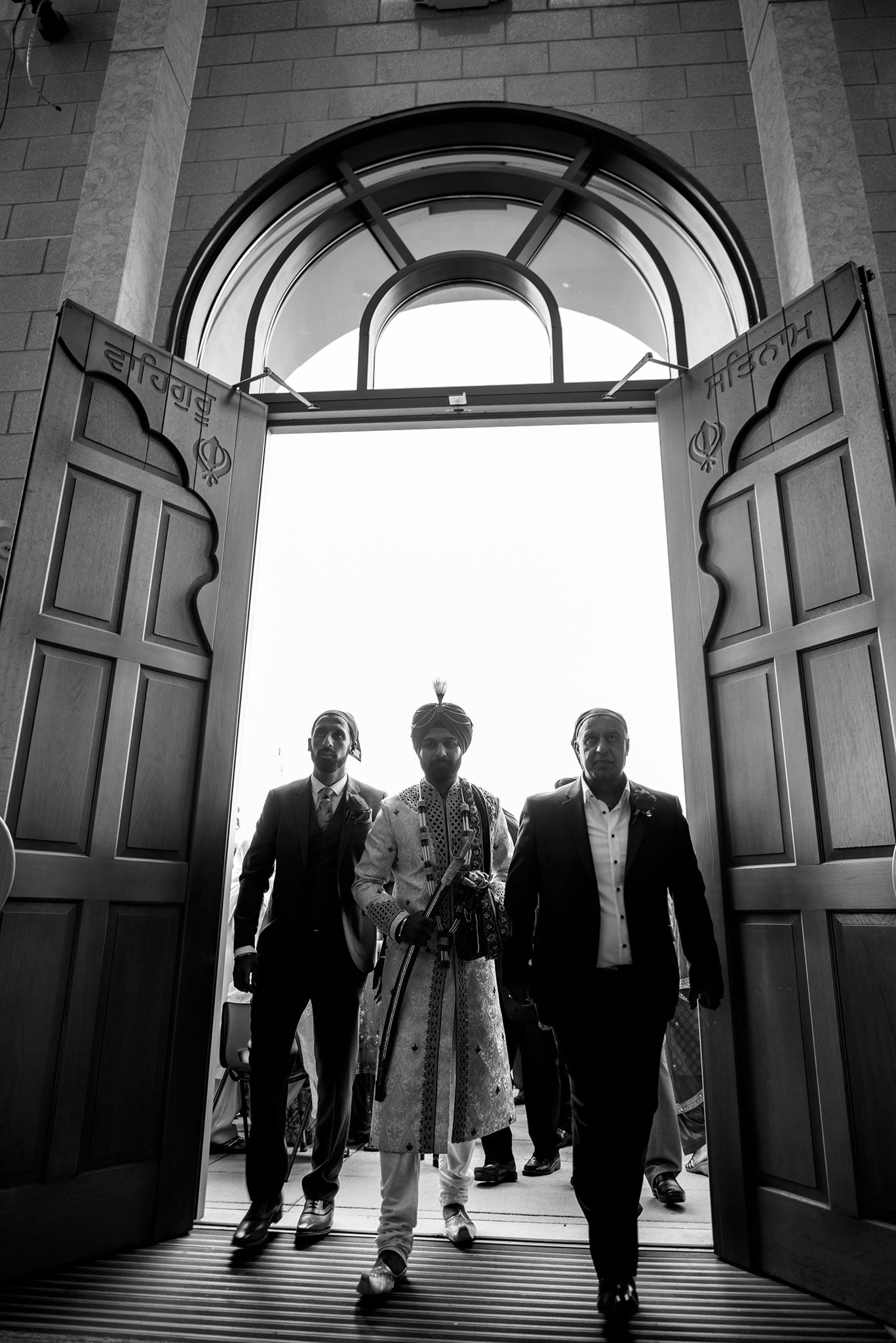 Dramatic black and white shot of people walking through ornate doorways.