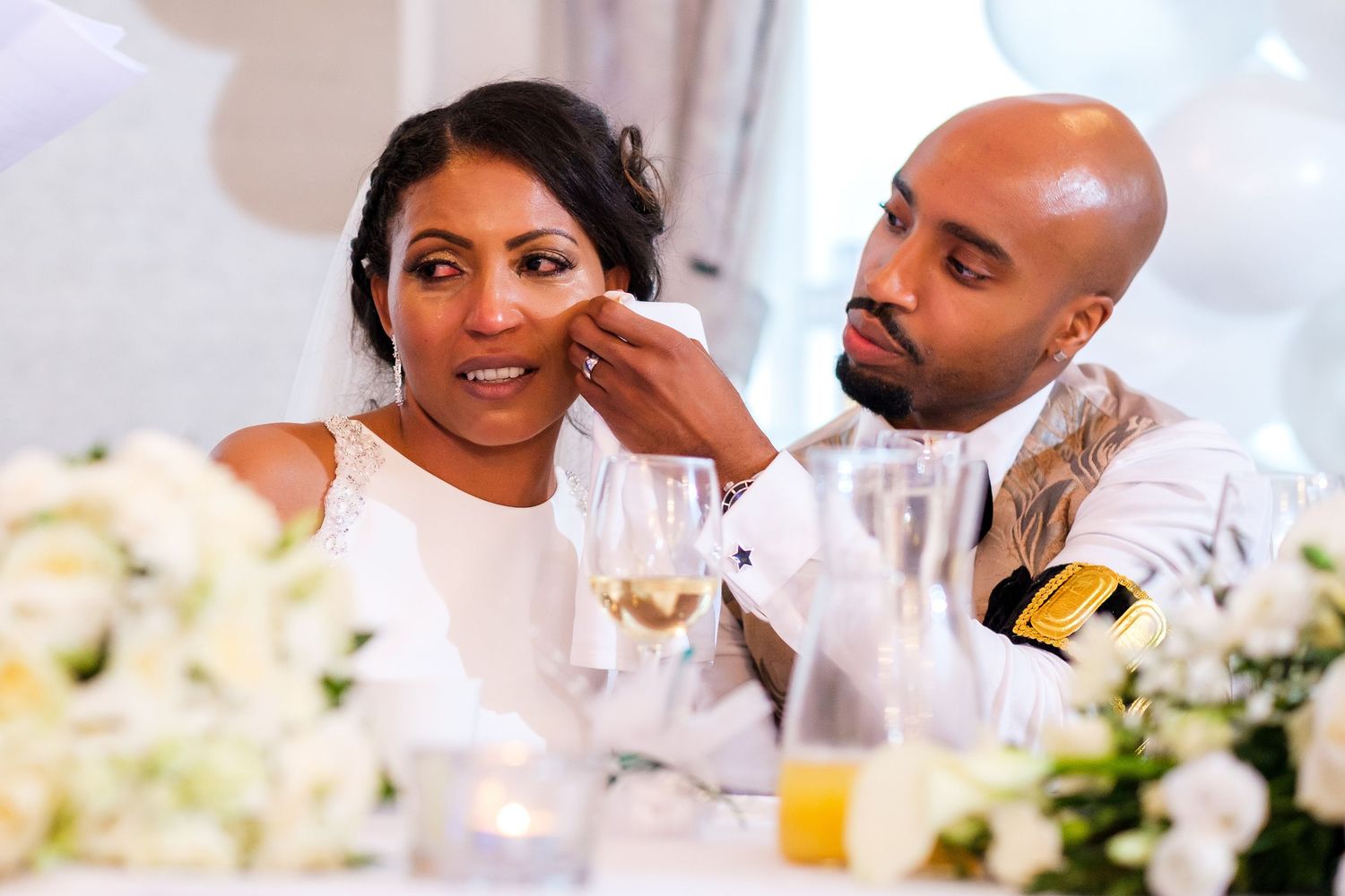 Couple sharing an intimate moment at their reception table decorated with white floral centerpieces.