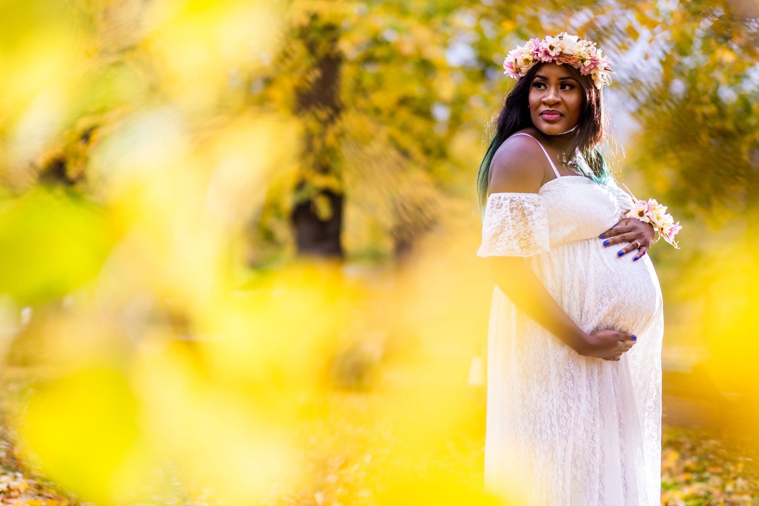 Golden sunlit outdoor maternity session with soft yellow bokeh effects.