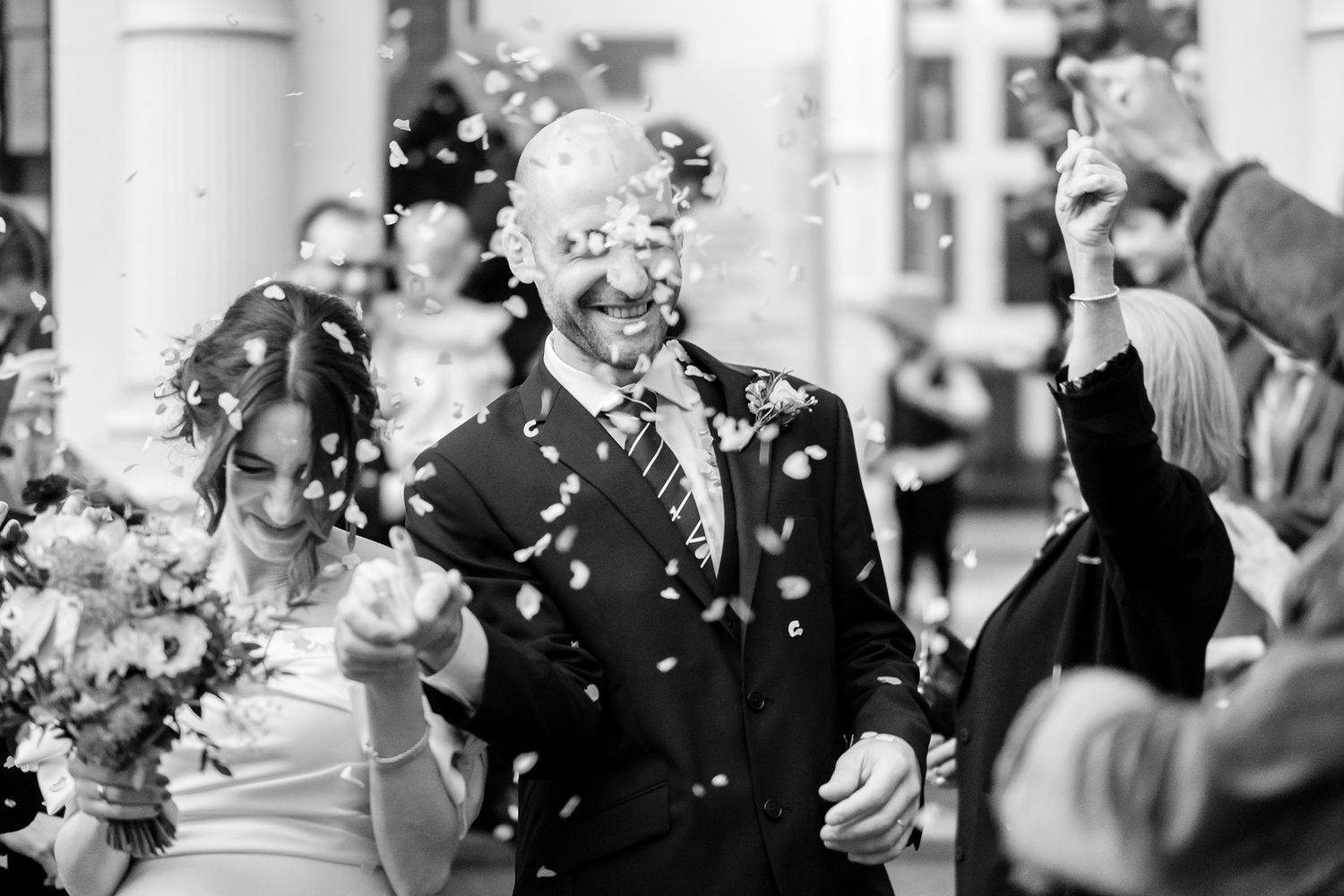 Wedding party celebration with confetti shower in an elegant indoor setting.