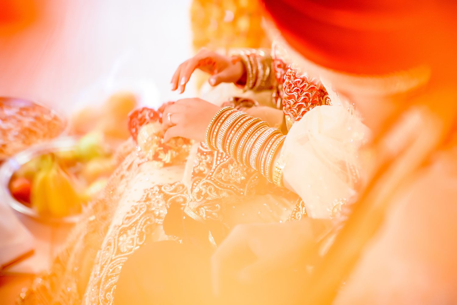 Abstract orange-tinted wedding photography highlighting ceremonial moments.