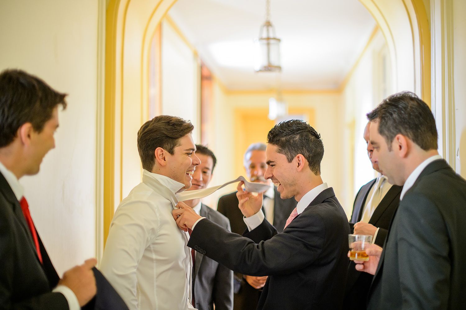 Wedding guests mingling and conversing in a bright hallway with classic architectural details.