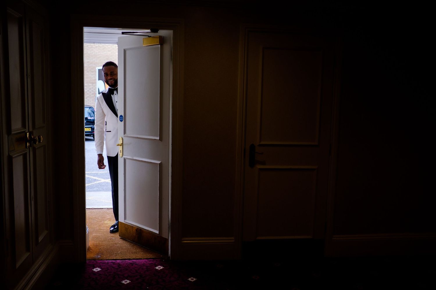 Silhouetted figures seen through doorway in dark atmospheric hallway.