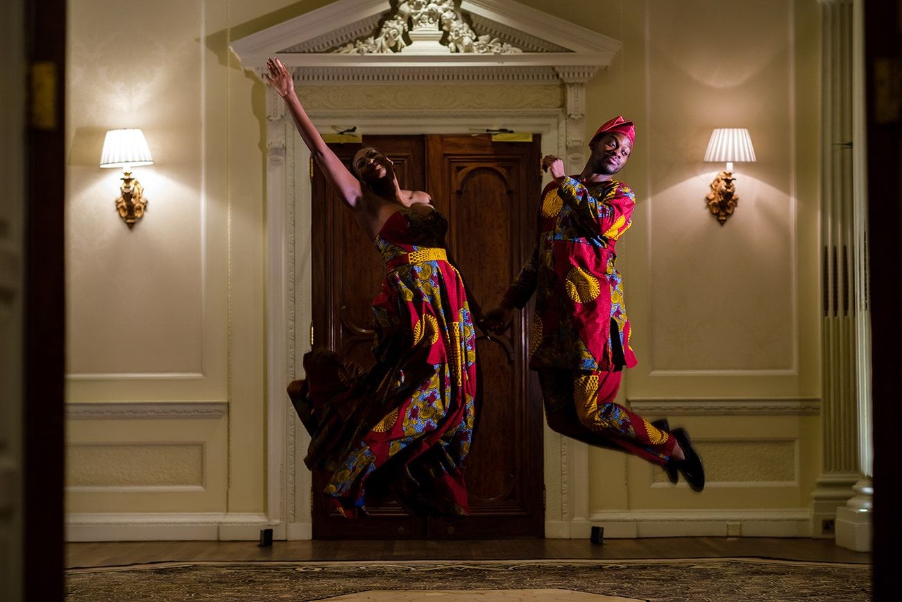 Performers in colorful costumes dancing against classic interior architecture.