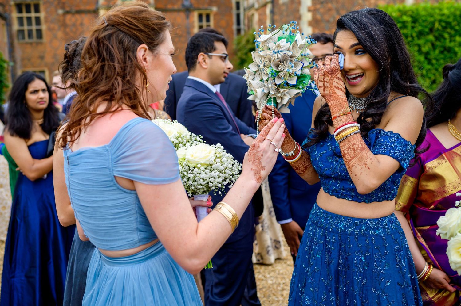 Wedding guests in blue dresses dance and celebrate during an outdoor reception.