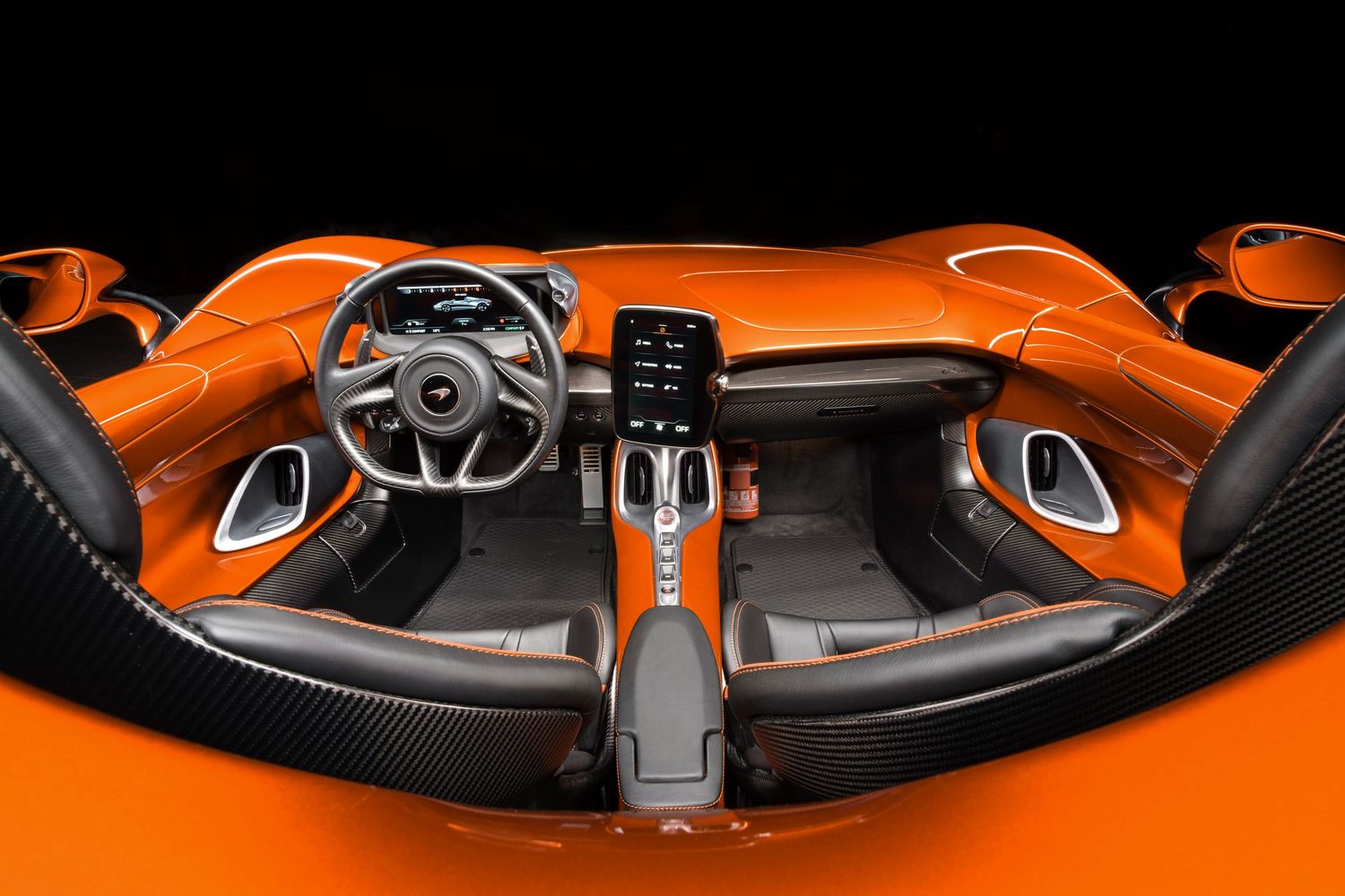 Interior dashboard view of a luxury orange sports car showing modern controls and steering wheel design.