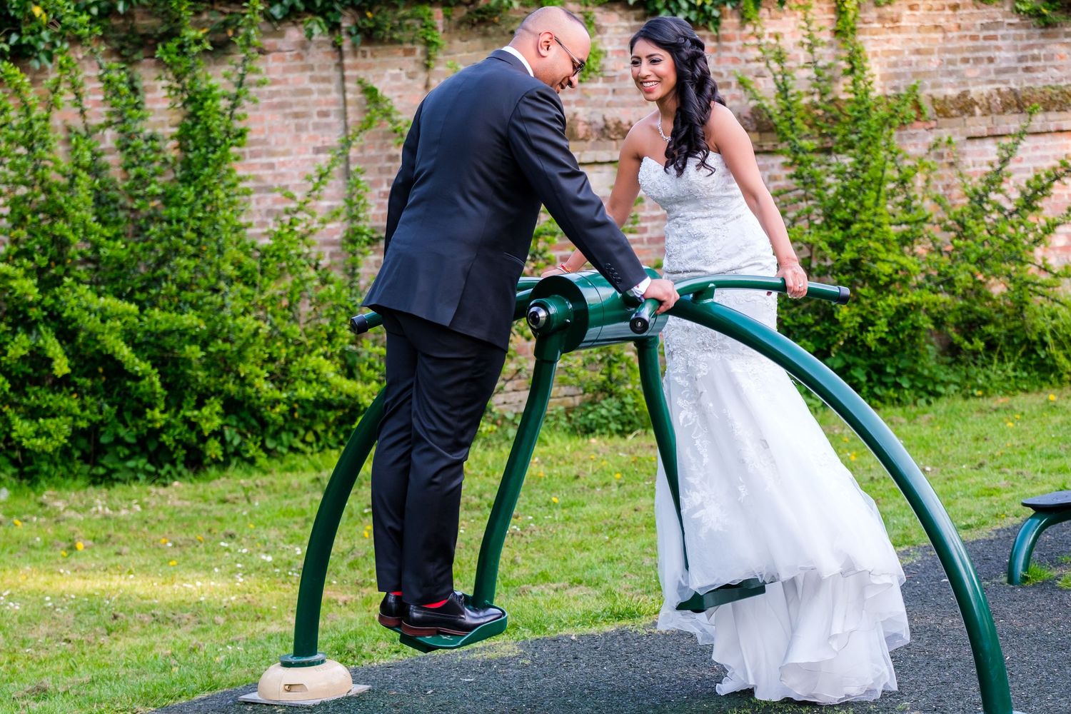 Playful garden wedding photos with couple posing near green foliage.