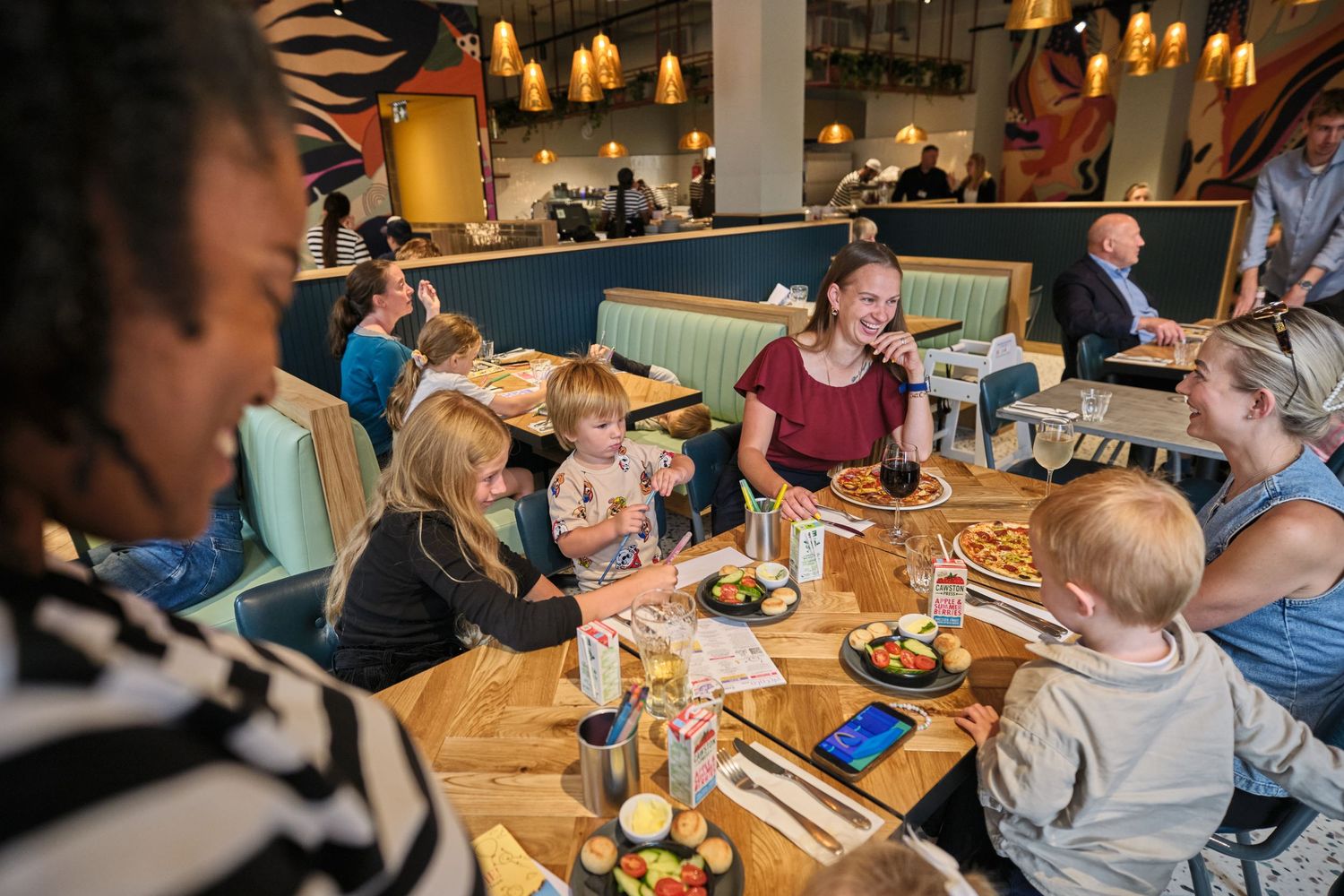 Diners enjoy a cozy evening meal at wooden tables illuminated by warm candlelight in a restaurant setting.