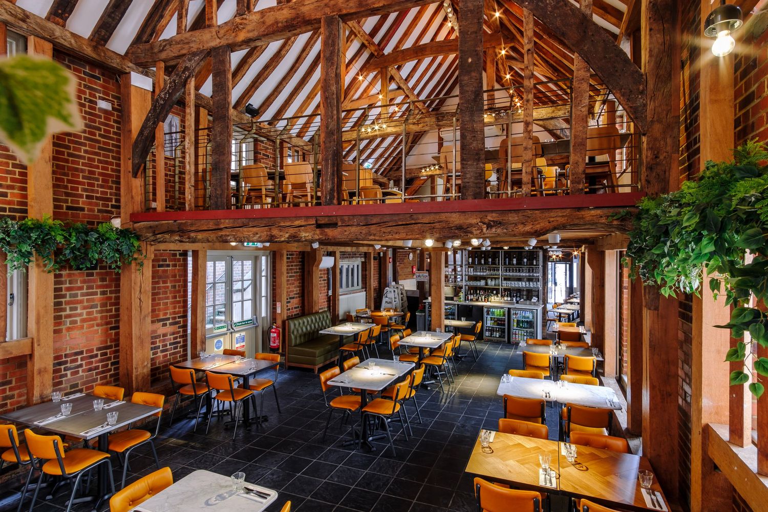 Rustic restaurant interior with exposed wooden beams and brick walls in warm lighting.