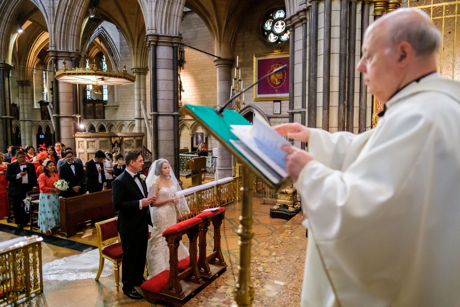 Ornate cathedral interior with gothic architecture features clergy members during ceremonial procession.