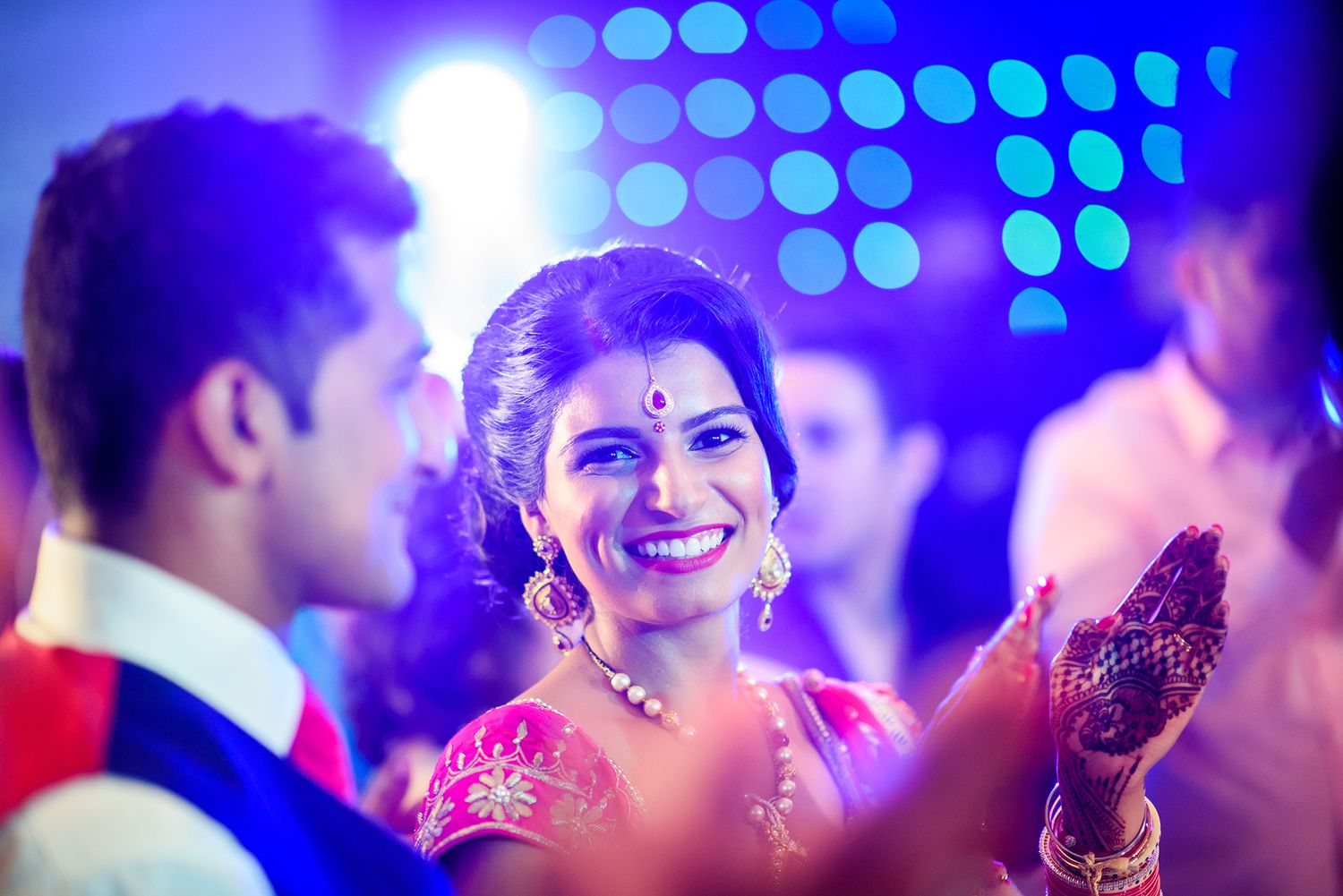Blue spotlights illuminate a festive dance floor with bokeh effects during an evening celebration.