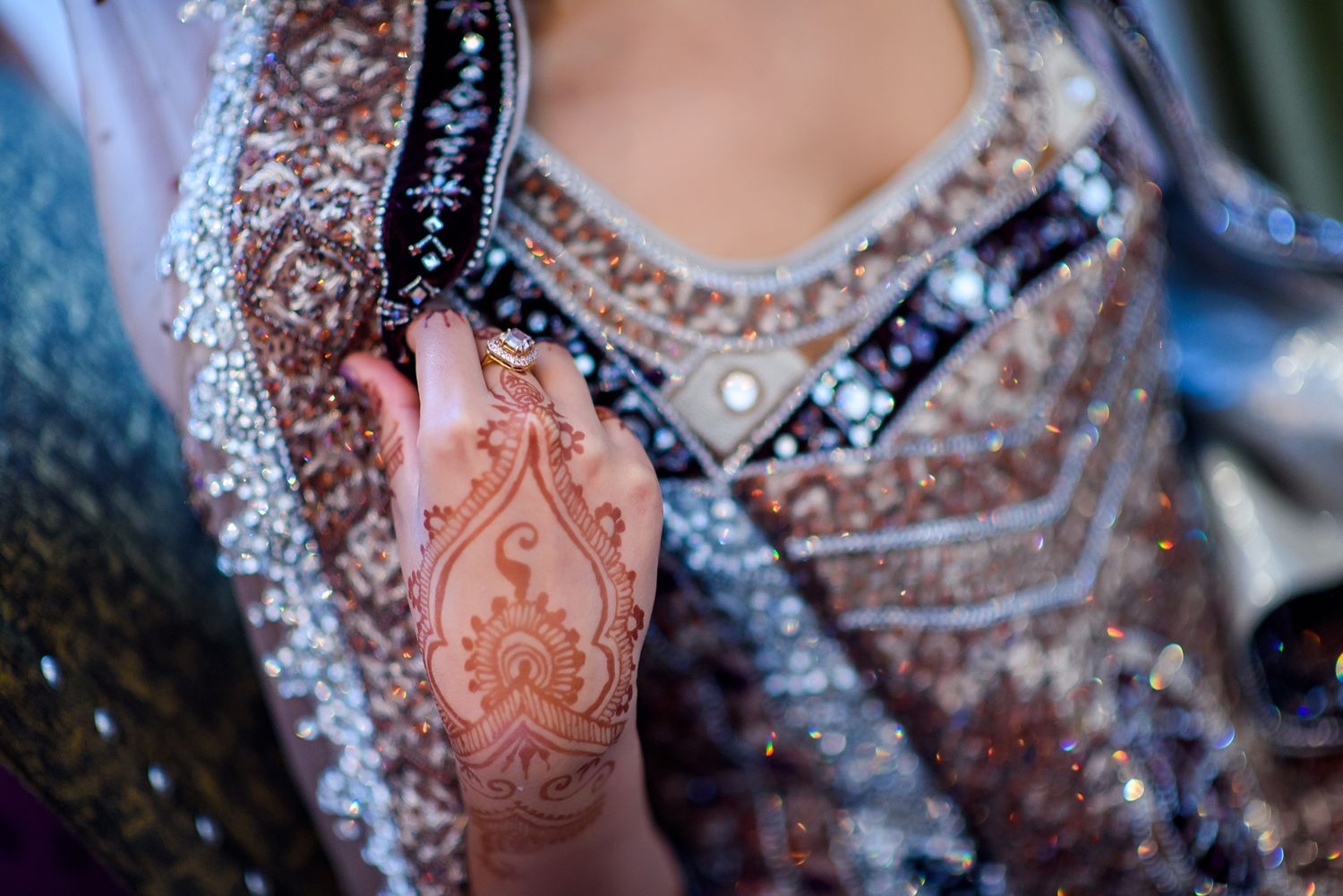 Detailed shot of ornate Indian bridal attire with embellishments and henna designs.
