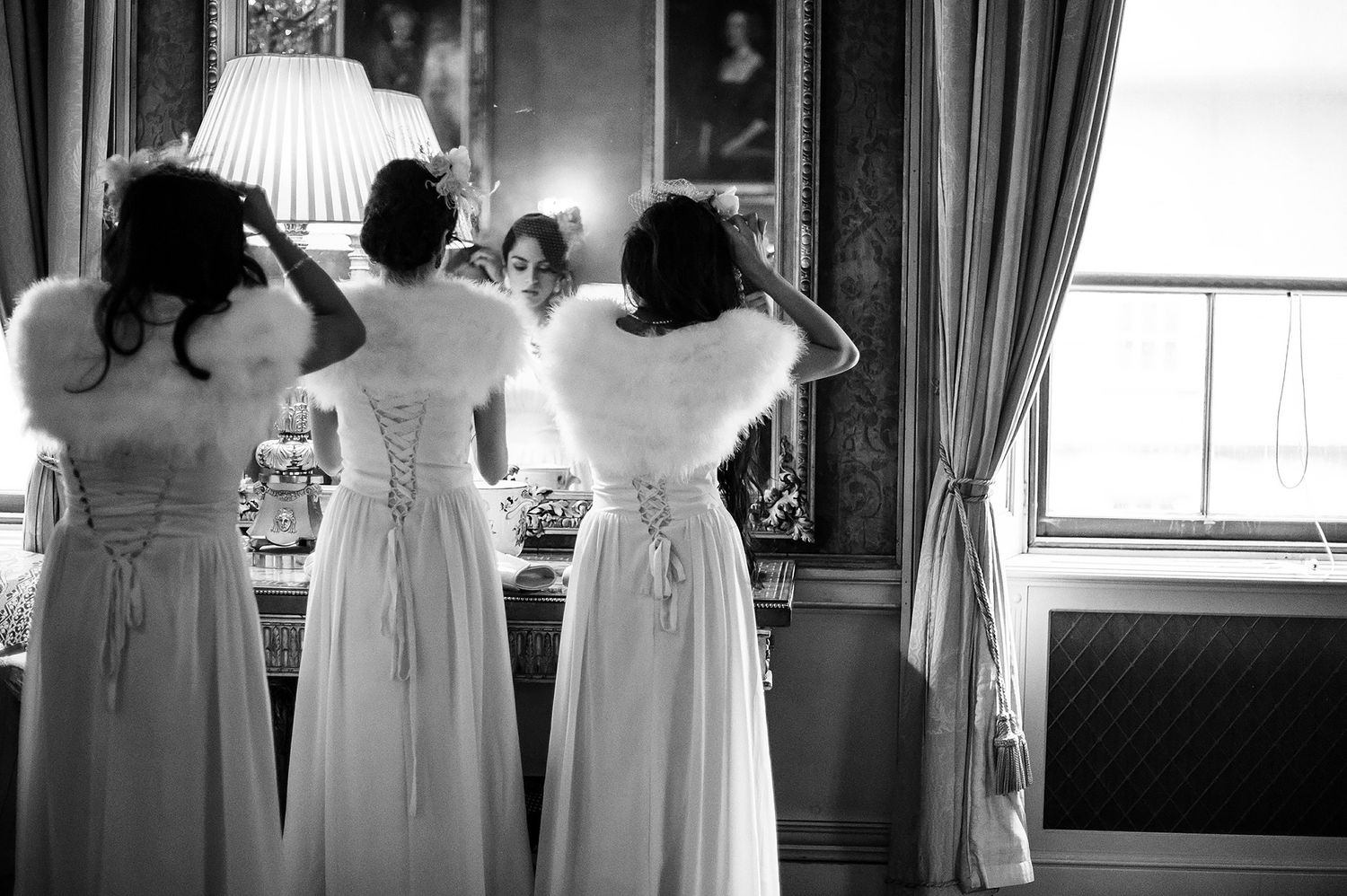 Side view of bridesmaids lined up in matching light pink dresses against ornate wall decor.