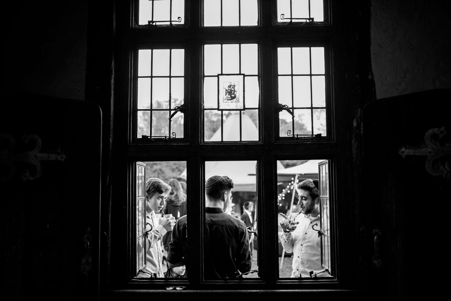 Dramatic silhouette of guests seen through large Gothic church windows.