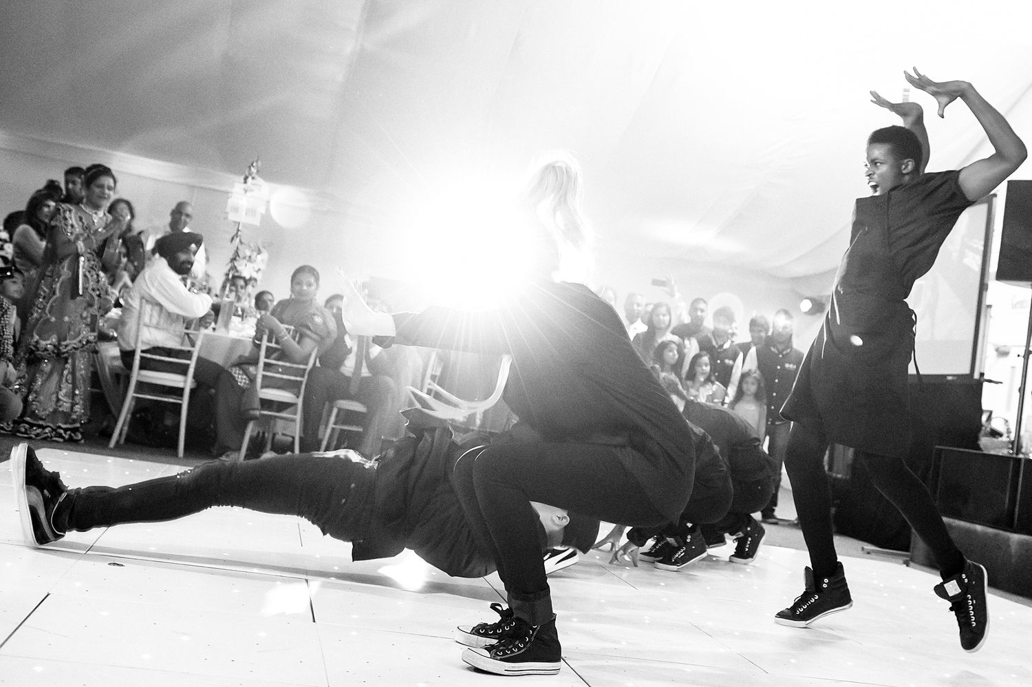 Black and white photo of energetic dance moves at a wedding reception.