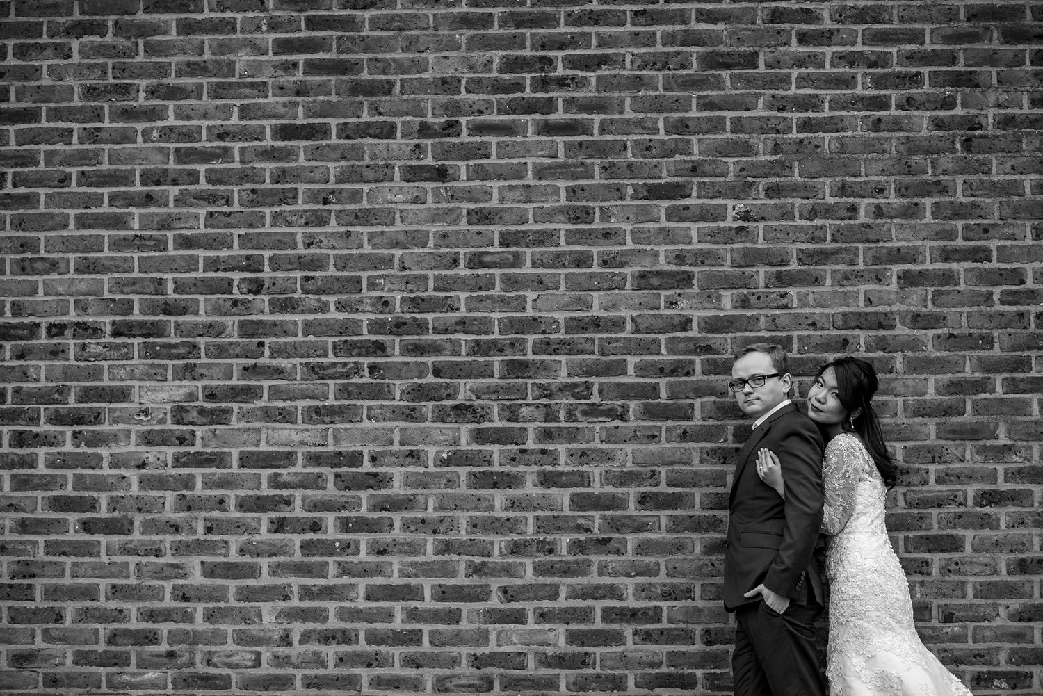 A dramatic wedding portrait against a classic red brick wall.