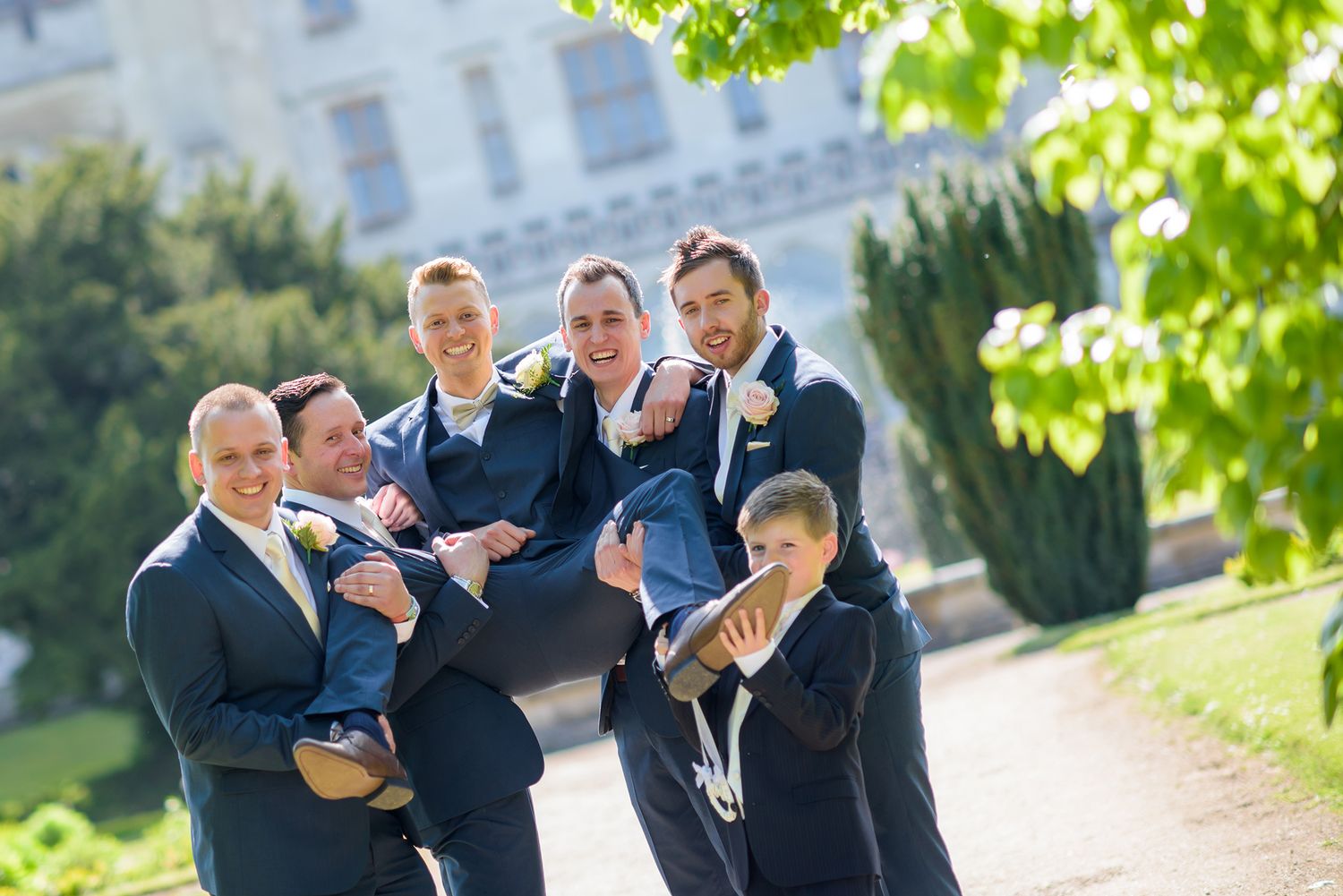 Wedding party celebrating and jumping together on garden path.