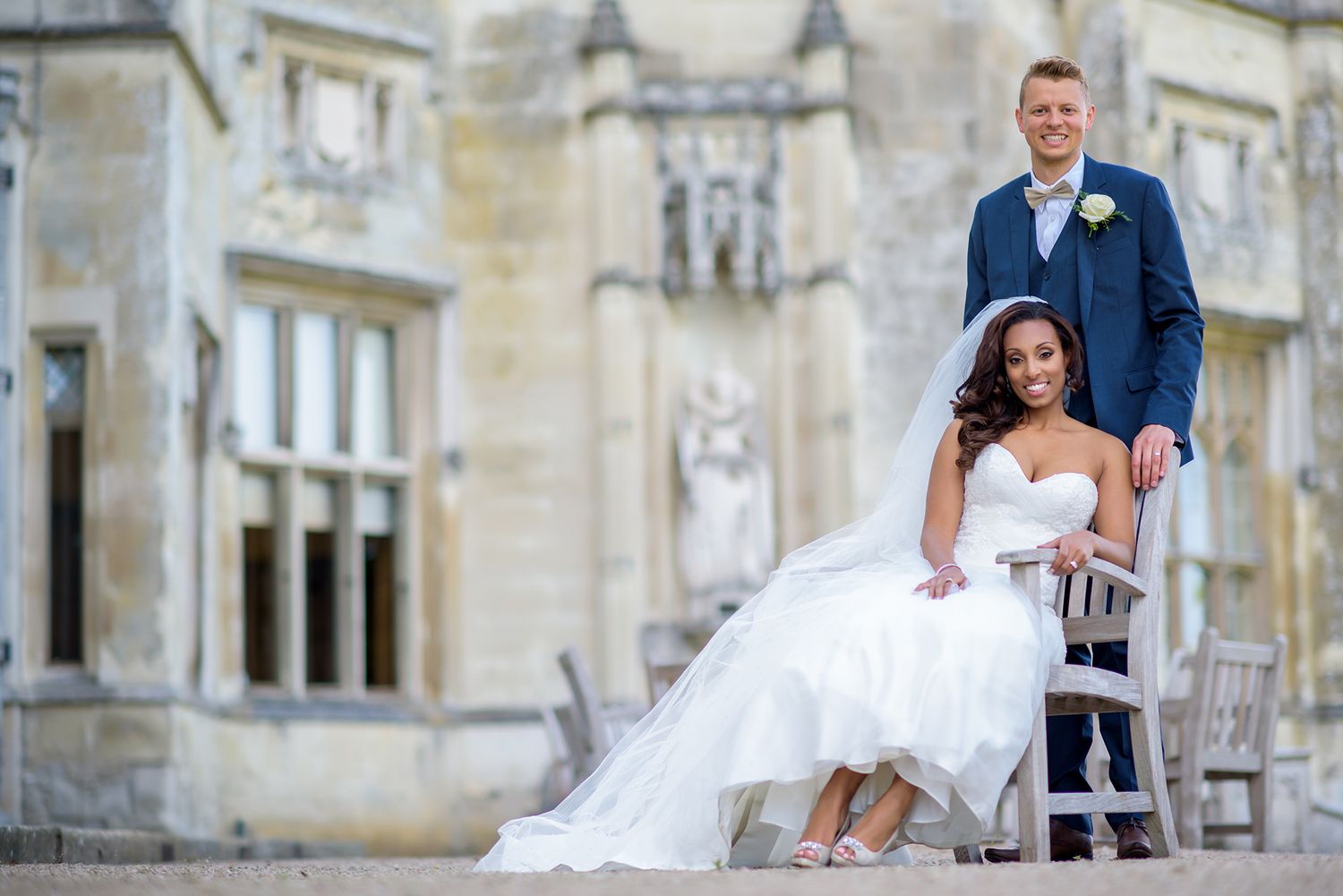 Wedding couple poses on stone steps of historic mansion.